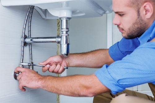 plumber working under sink