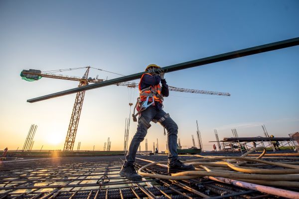 Construction worker carrying a beam on site