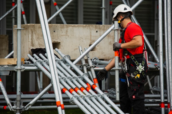Worker Next to Scaffolding Stack