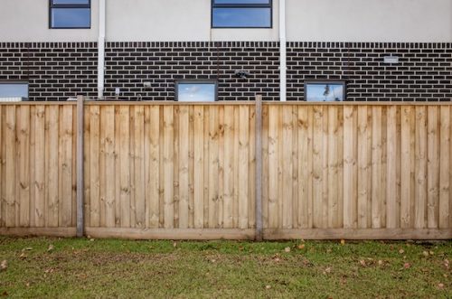 A vertical wooden fence installed in front of a modern house in suburban Australia. Wooden boundary fencing used in new residential developments, emphasizing privacy, residential property division. new property development needing insurance