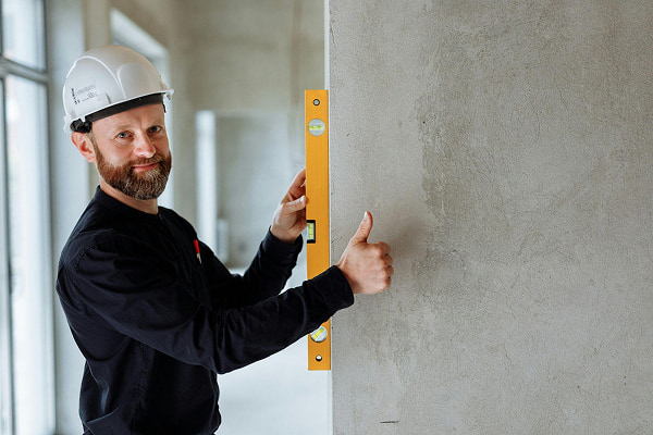 A construction manager in white hard hat holding a yellow spirit level
