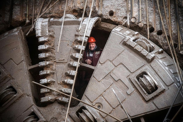 Construction worker in safety gear standing in a tunnel boring machine on an underground civil engineering project.