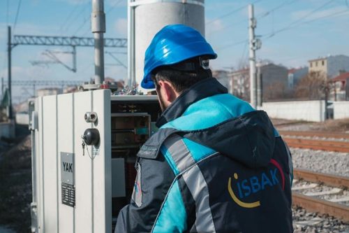 Electrician carefully examining fuse box components during electrical safety inspection at train tracks.